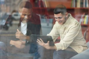 Un salarié en tenue de terrain (technicien ou ouvrier) consultant une tablette numérique à côté d’un équipement industriel, en pleine action.